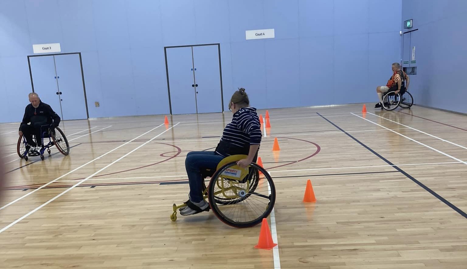 Wheelchair tennis participants manouvering around cones
